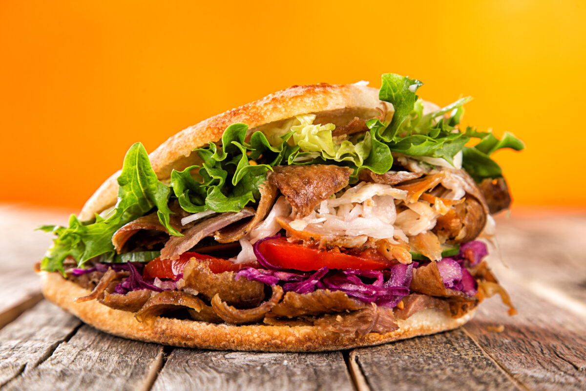 Close up of tasty kebab sandwich on old wooden table.