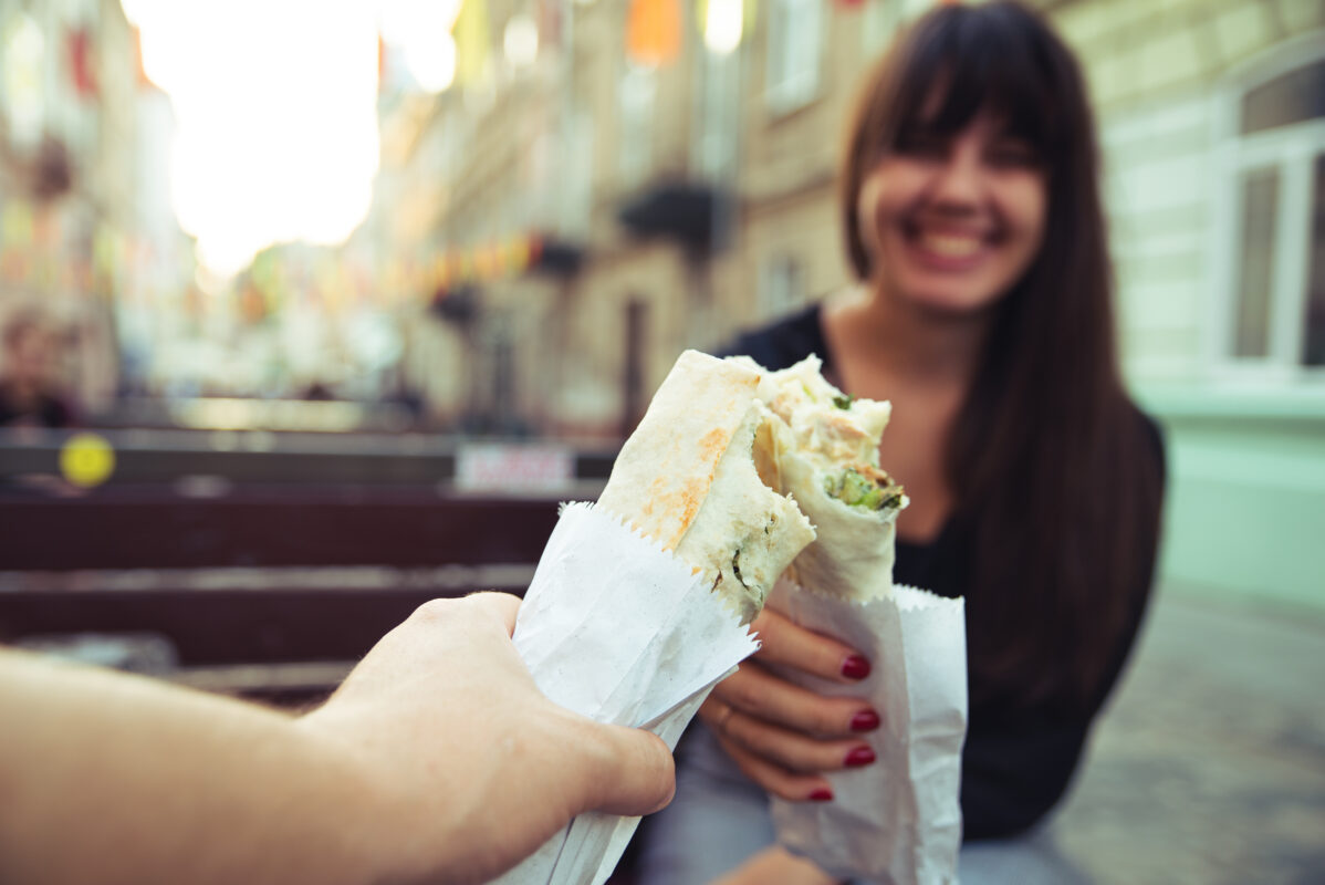 young smiling woman eating fast food outdoors urban rush lifestyle